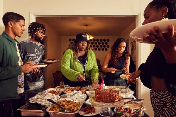 A group of five people serve themselves food from the table.